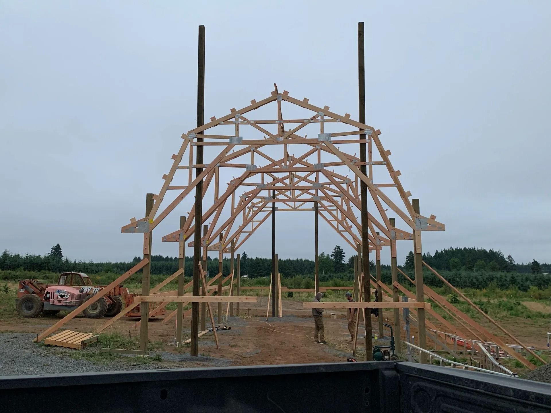 Wooden barn frame under construction with arched roof.