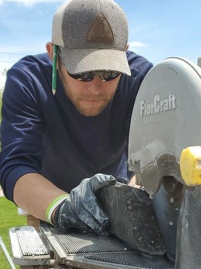A man wearing a hat and sunglasses is working on a fiorcraft machine
