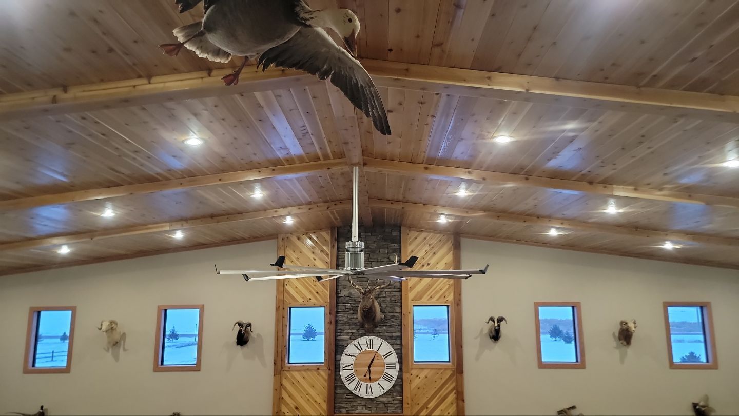 A ceiling fan is hanging from the ceiling of a room with a clock on the wall.