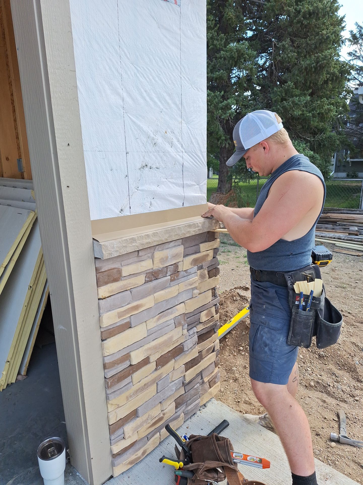 A man is installing stone siding on a building.