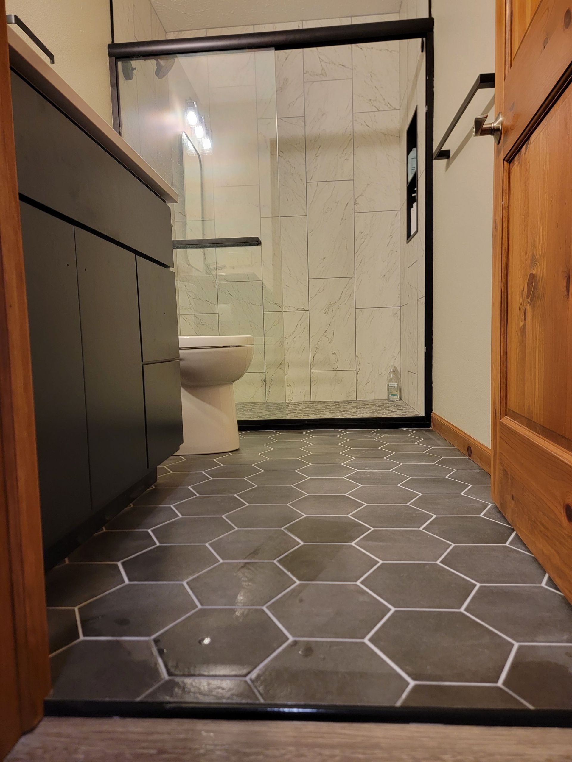 A bathroom with a hexagonal tile floor and a toilet