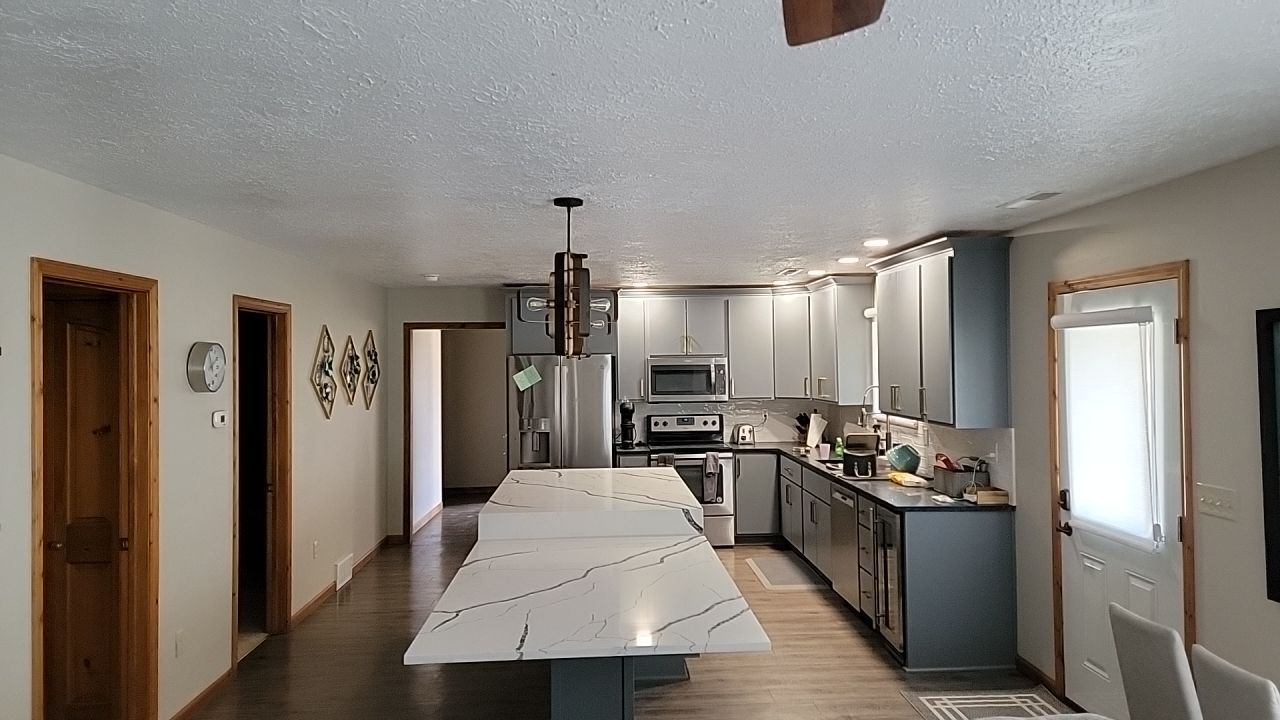 A kitchen with a large island in the middle and stainless steel appliances.