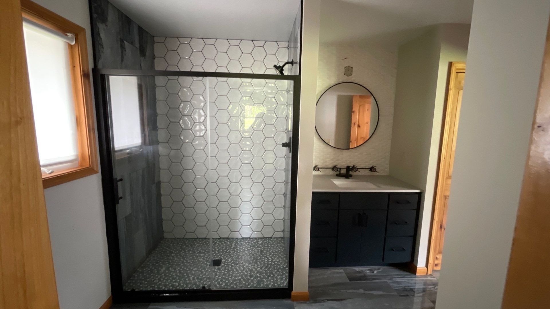 A bathroom with a walk in shower , sink and mirror.