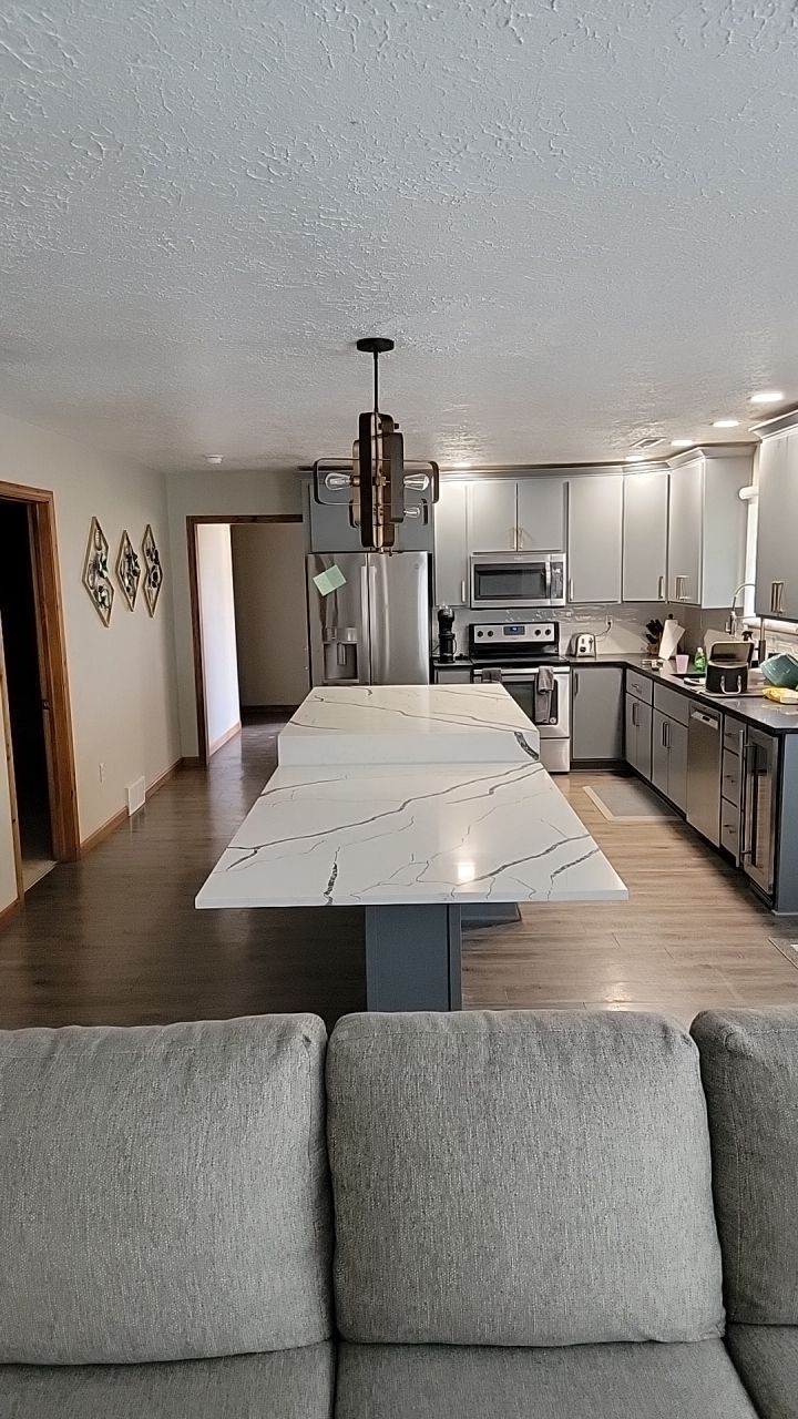 A living room with a couch and a kitchen with a large island.
