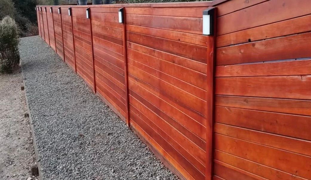 A wooden fence is sitting on top of a gravel road.