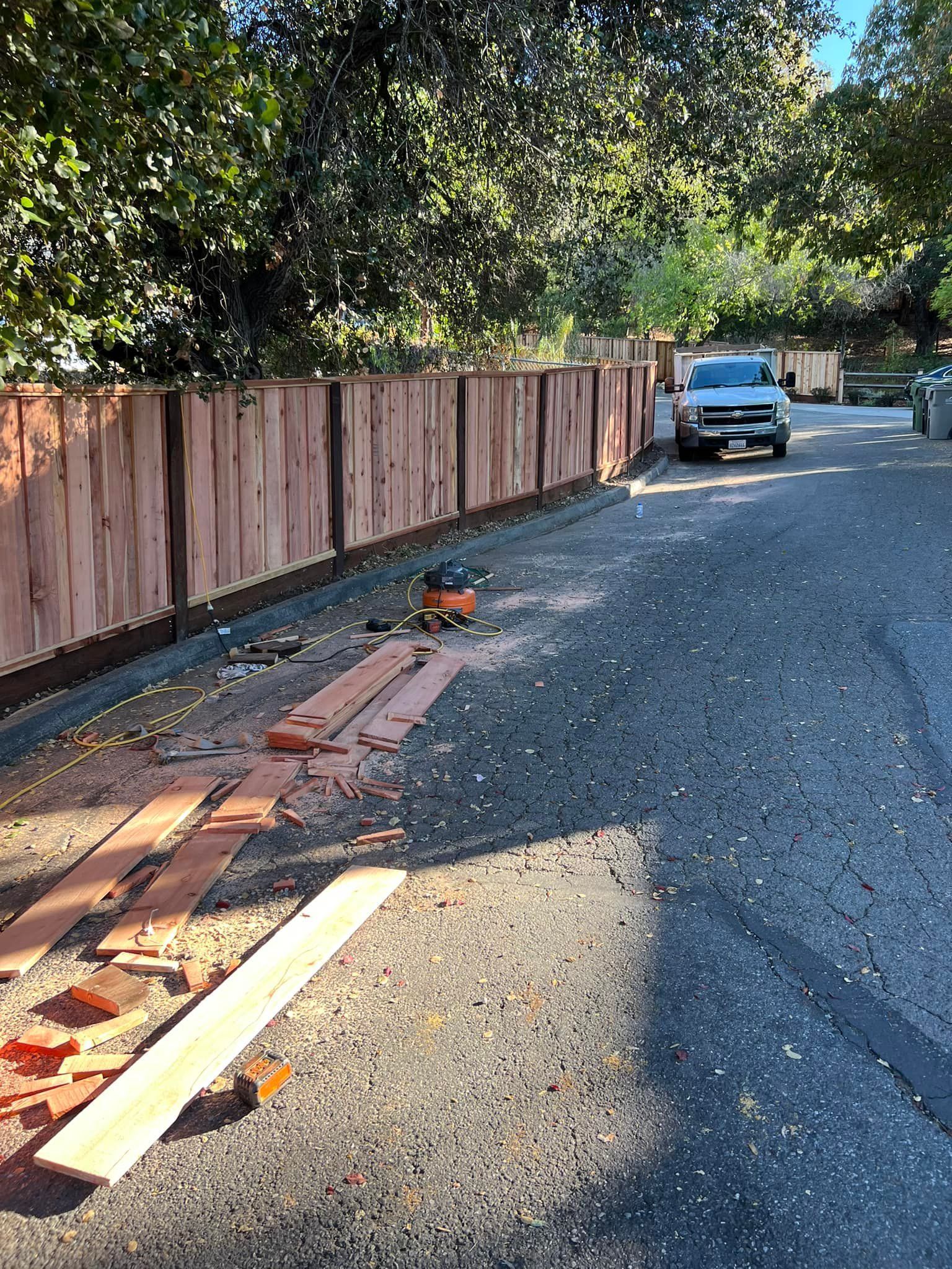 A wooden fence is being built on the side of the road.