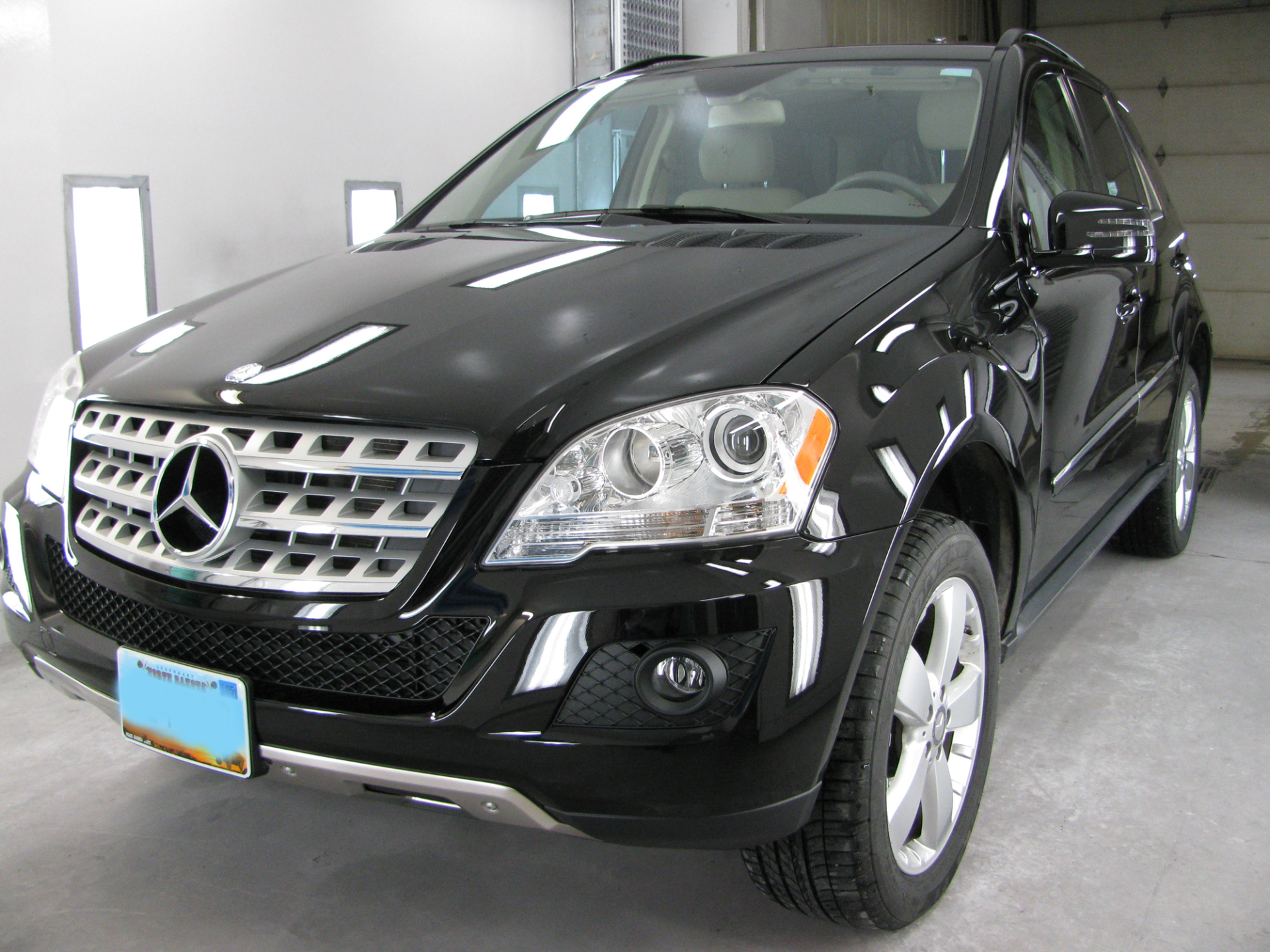Black Mercedes-Benz SUV parked in a garage, featuring a silver grille and license plate from Minnesota.