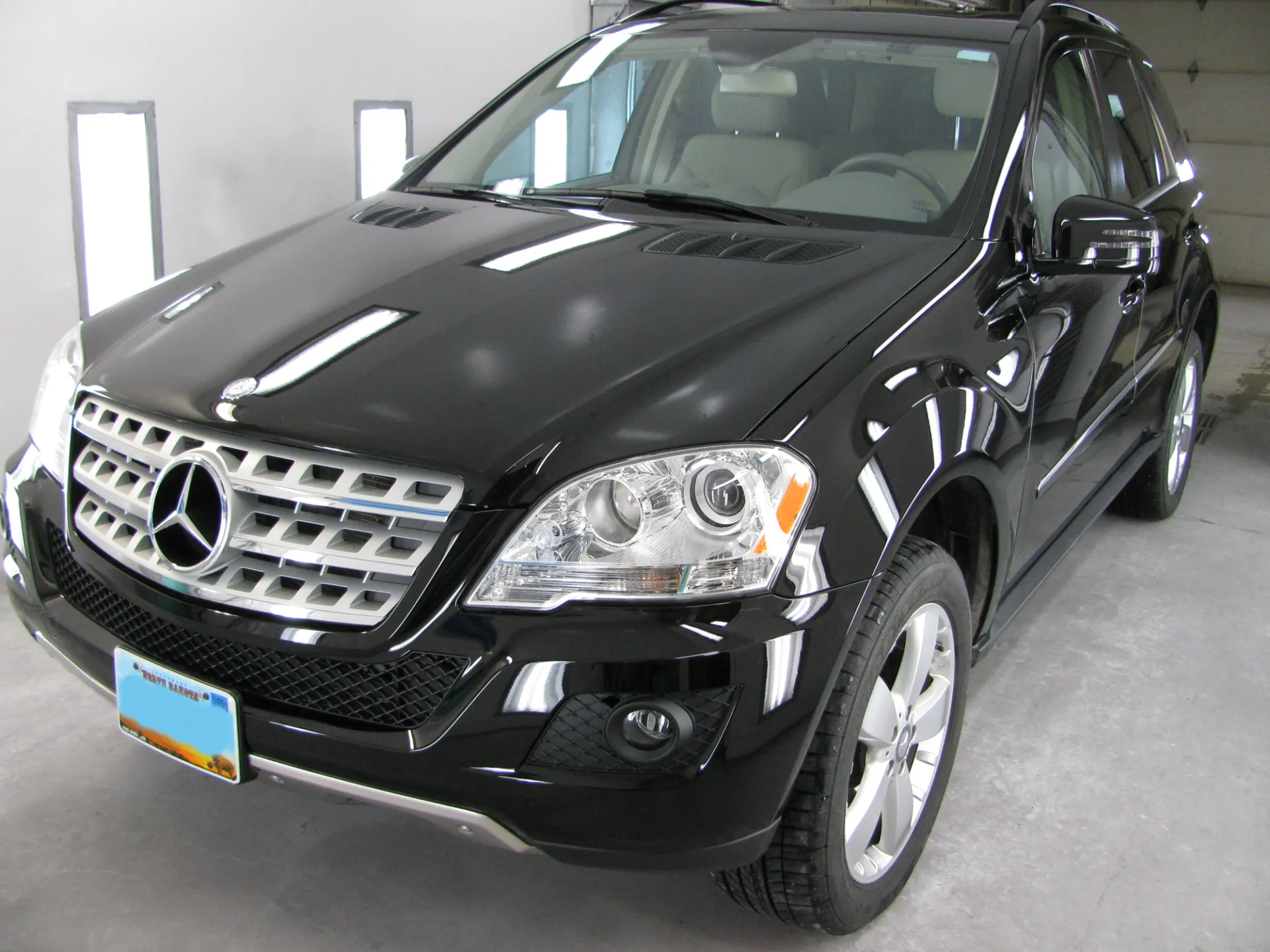 Black Mercedes-Benz SUV parked in a studio. Front view, shiny black paint, silver grille, and alloy wheels.