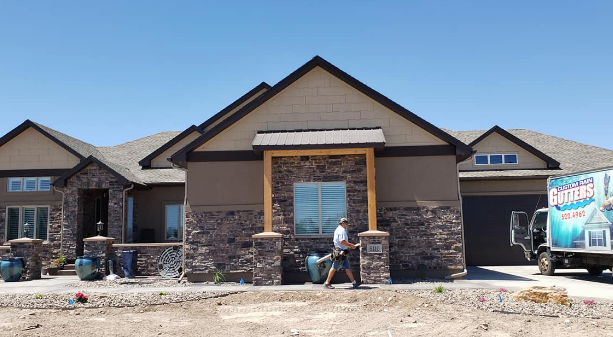 New house under construction with stone facade, workers at the entrance, and a delivery truck nearby