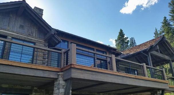 Rustic lodge with wood-and-stone balconies and large windows under a blue sky