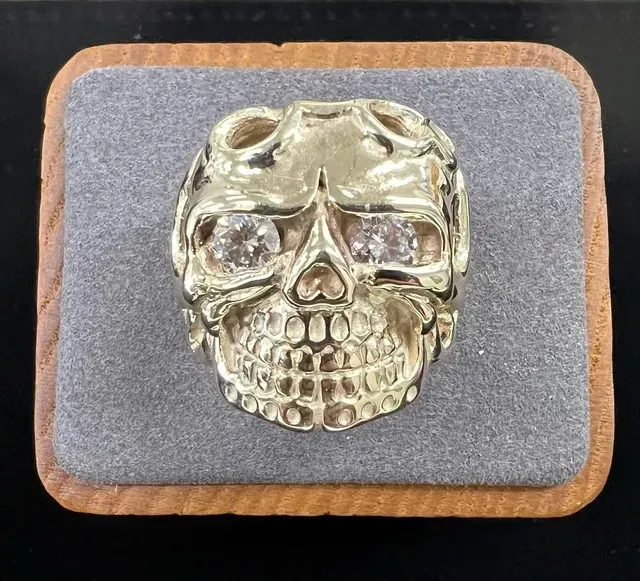 A gold skull ring is in a wooden box