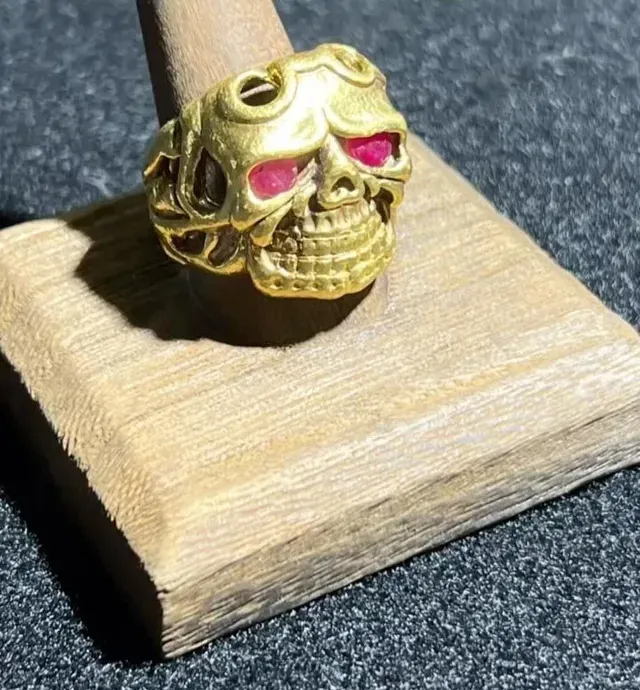 A gold ring in the shape of a skull with red eyes