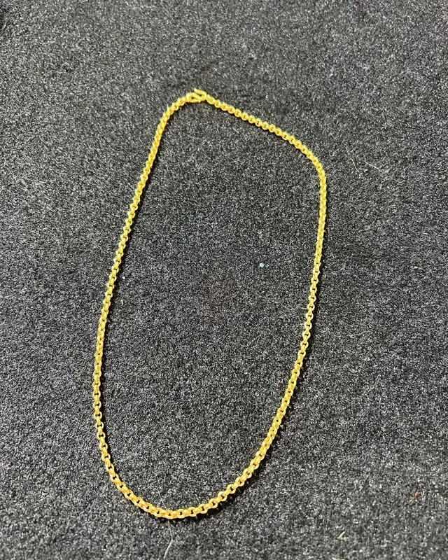 A gold chain is sitting on a gray surface.