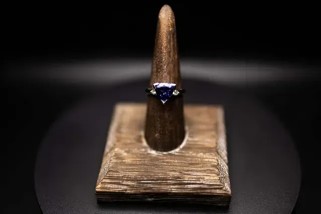 A ring is sitting on top of a wooden ring holder.