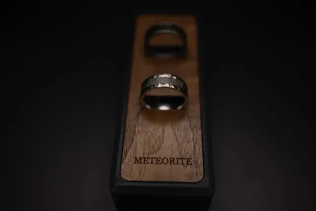 Two wedding rings are sitting on top of a wooden box.
