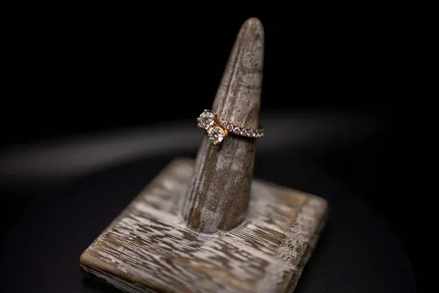 A ring is sitting on top of a wooden ring holder.