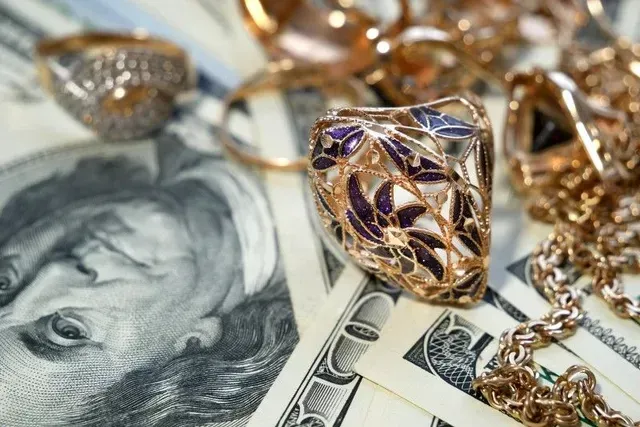 A diamond ring is sitting on top of a pile of money.