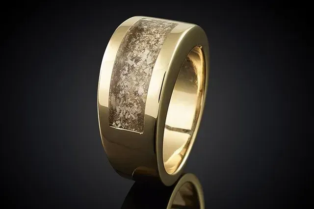 A close up of a gold ring on a black surface