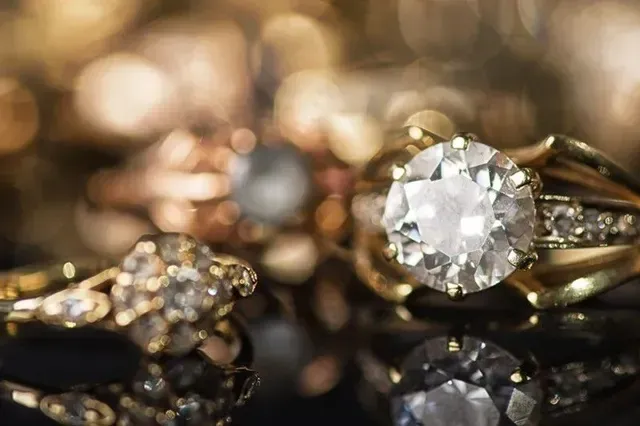 A close up of a diamond ring on top of a pile of gold rings.