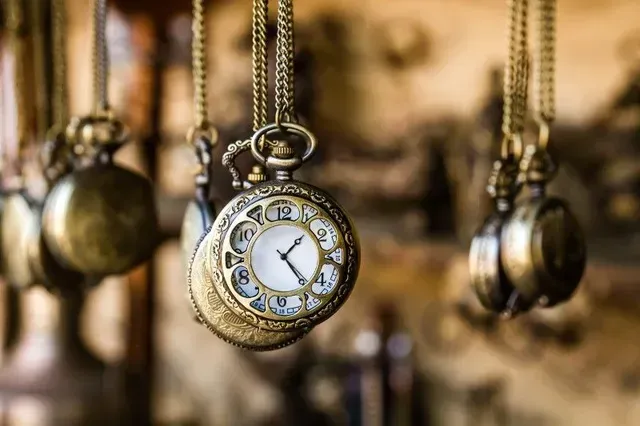 A close up of a pocket watch hanging from a chain.