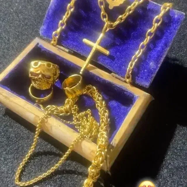 A wooden box filled with gold jewelry including a cross