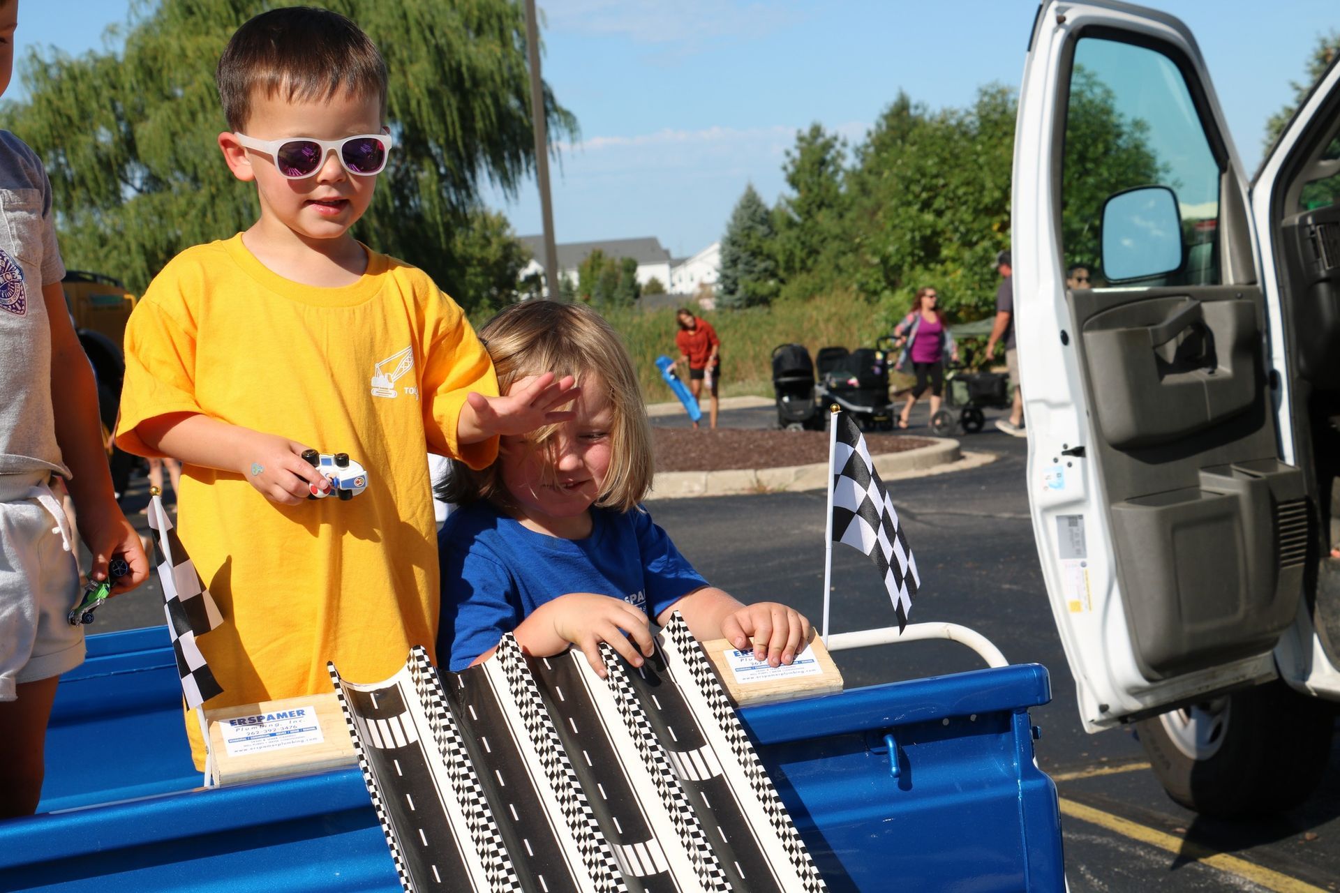 A boy and a girl are sitting in the back of a truck.