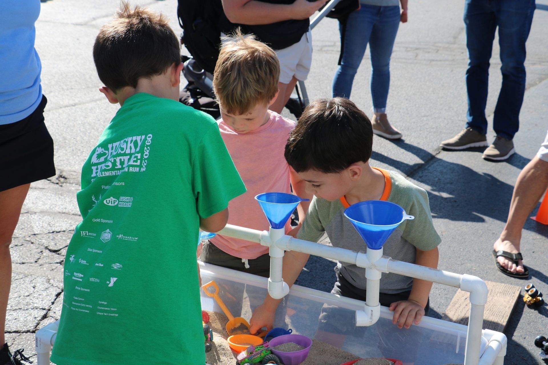 A boy in a green shirt is playing in a sandbox