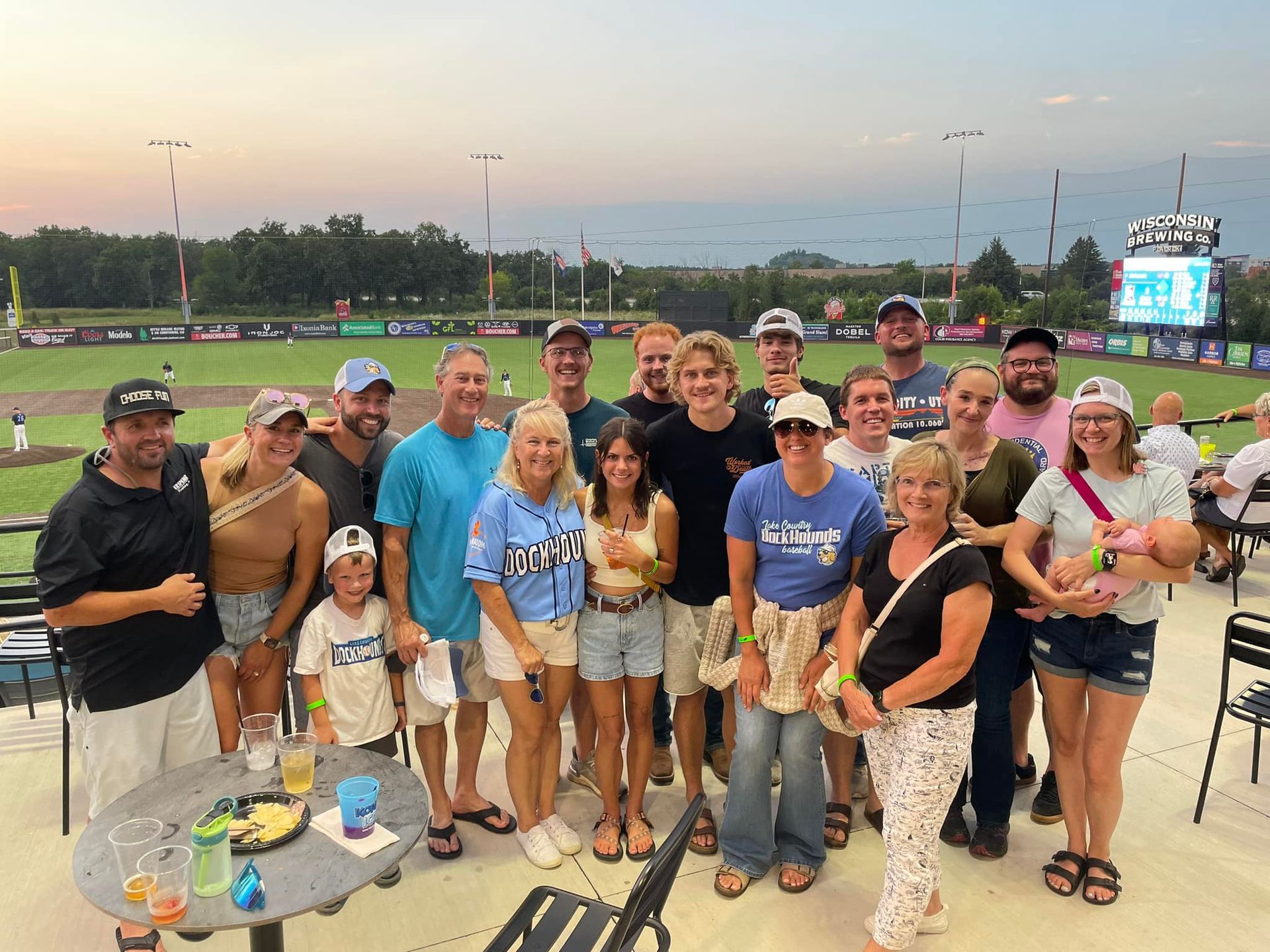 A group of people are posing for a picture in front of a baseball field.