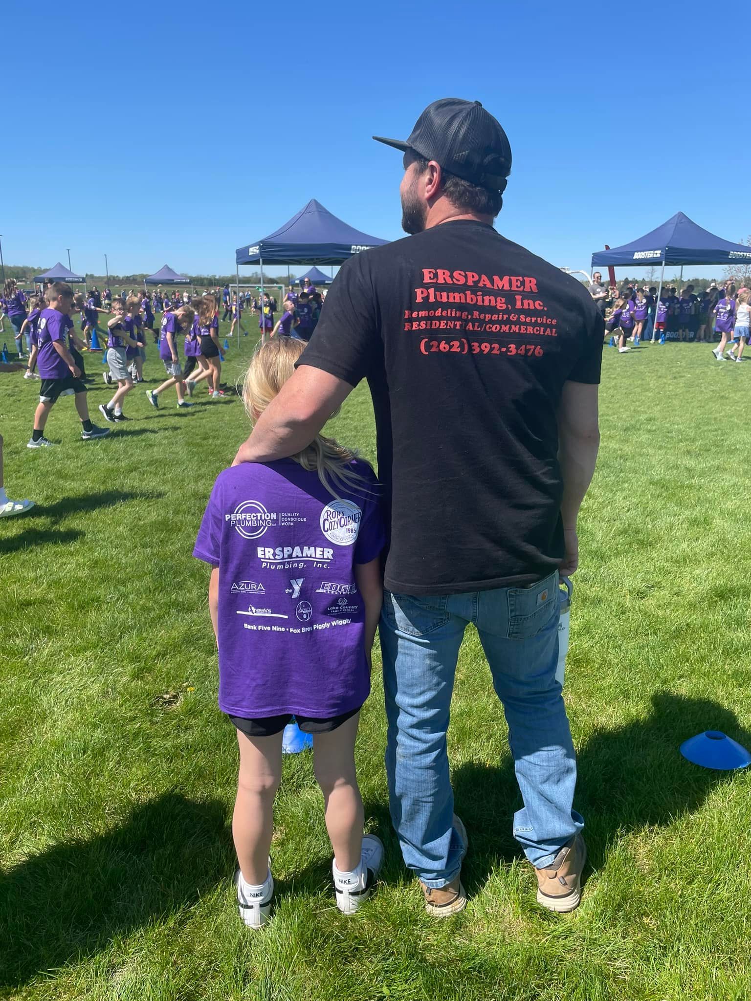 A man and a little girl are standing next to each other in a field.