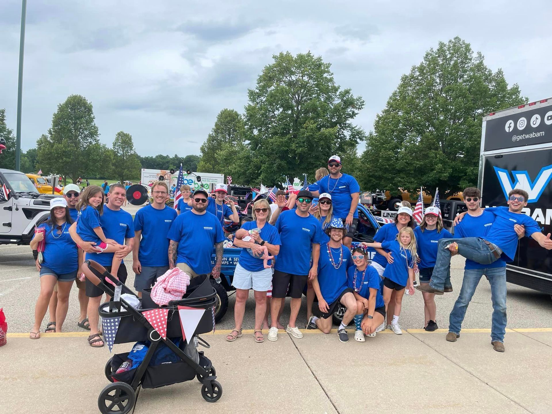 A group of people are posing for a picture in front of a truck.