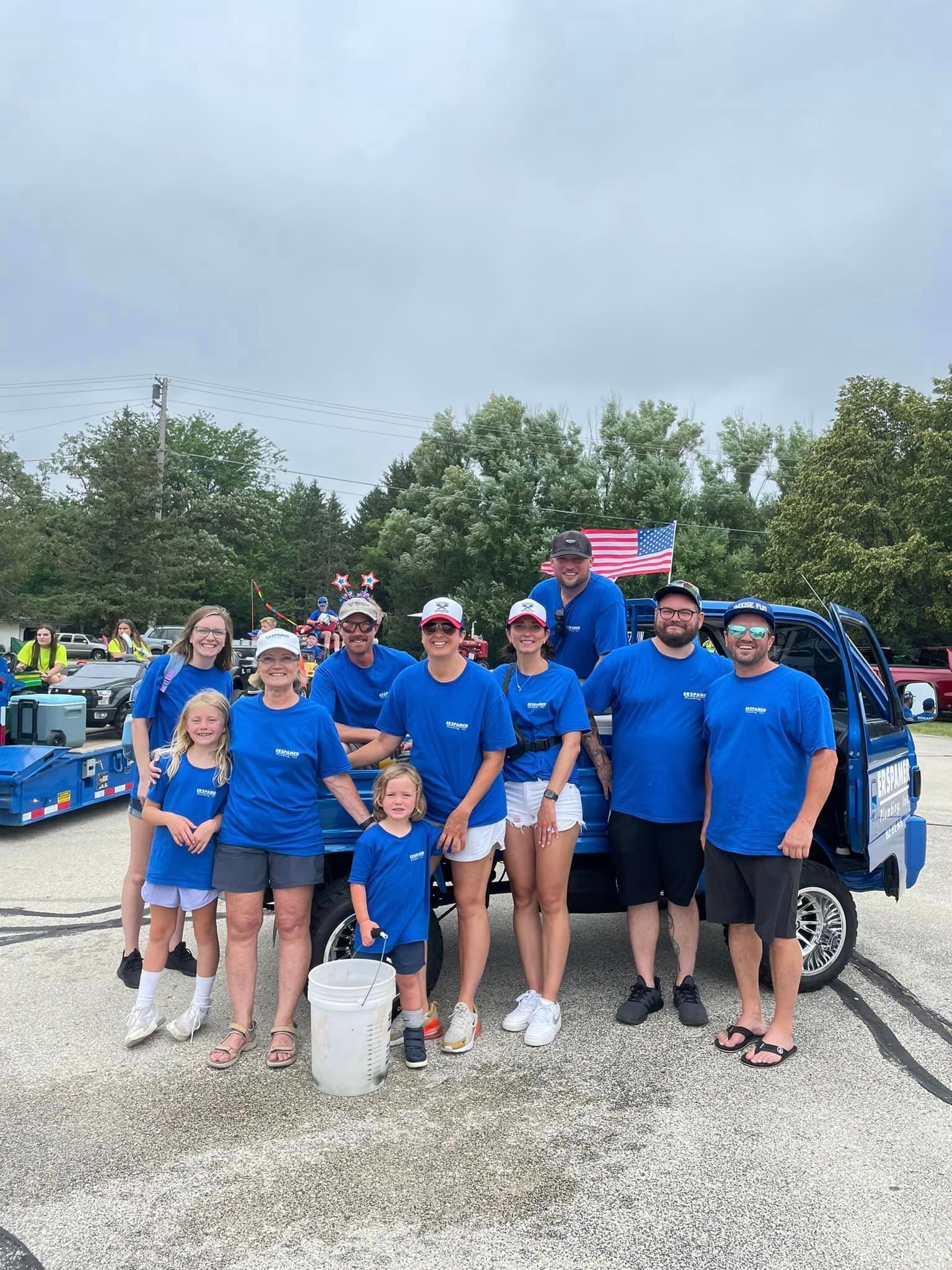 A group of people are posing for a picture in front of a truck.