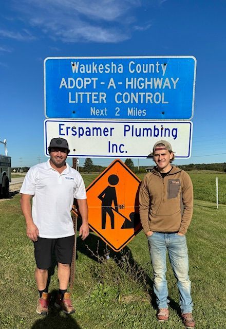 Two men are standing in front of a sign that says waukesha county adopt a highway litter control