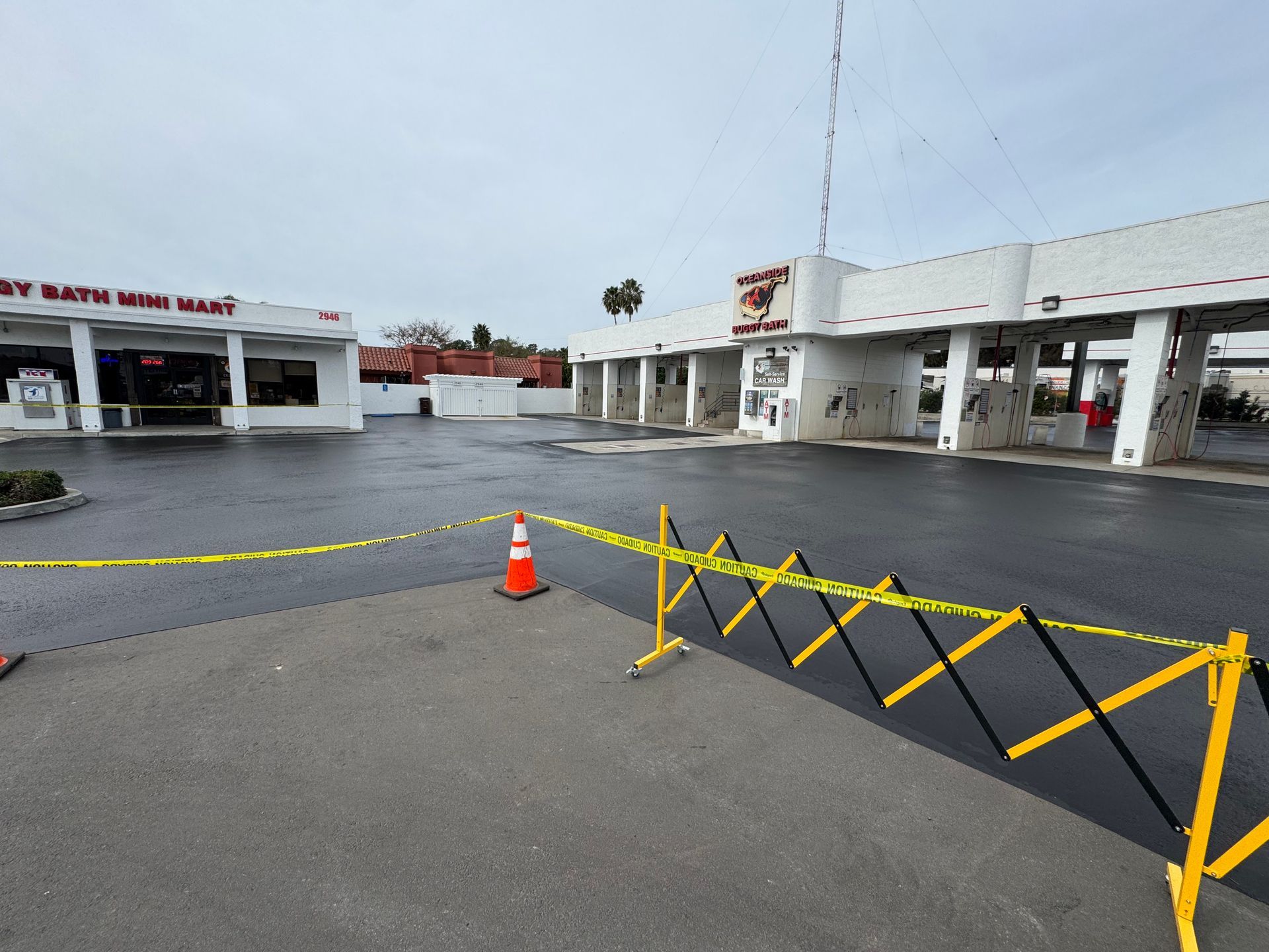 Empty parking lot with orange cone and yellow barricade in front of a white building row