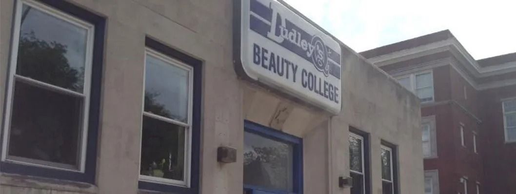 Exterior of a beauty college building with sign that reads "Beauty College".
