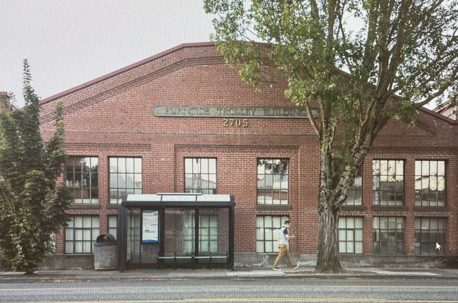 A brick building with a bus stop in front of it