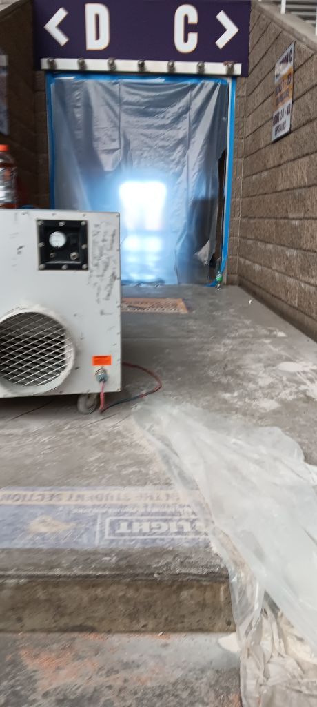 Entrance with signs for D and C, obscured by plastic sheeting, with an industrial machine in the foreground.