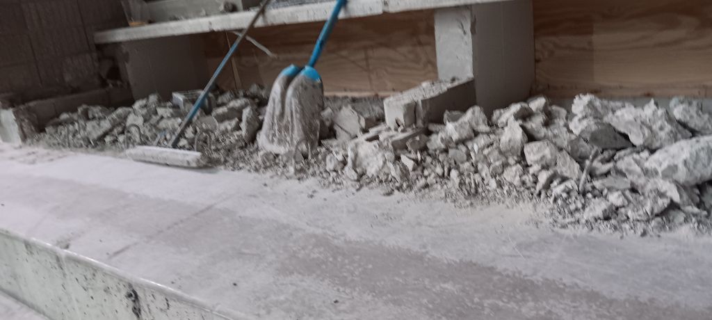 Construction debris on a concrete surface with a mop and other tools.