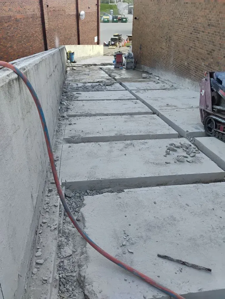 Concrete slabs cut on a pathway between two buildings, red hose, construction site.