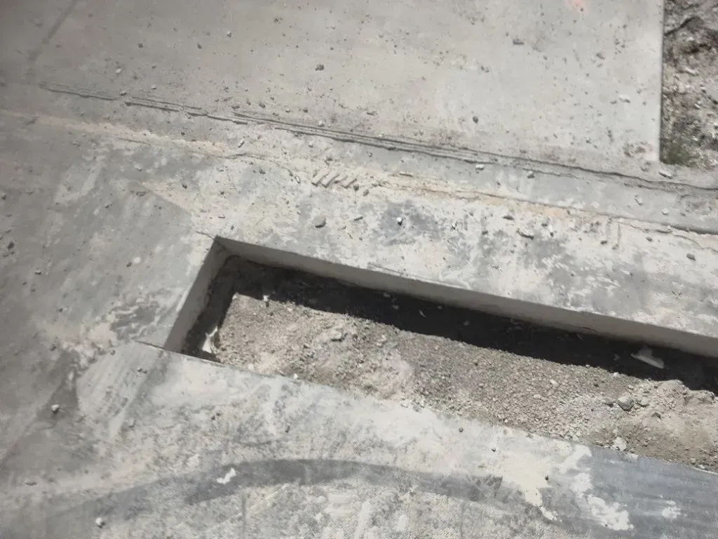 Concrete ramp with a recessed channel filled with small stones, likely for drainage.