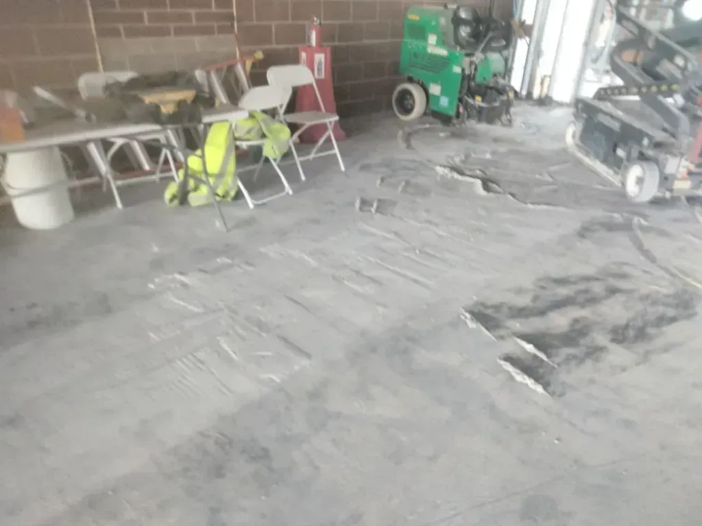 Damaged concrete floor in a workshop, with tools and equipment.