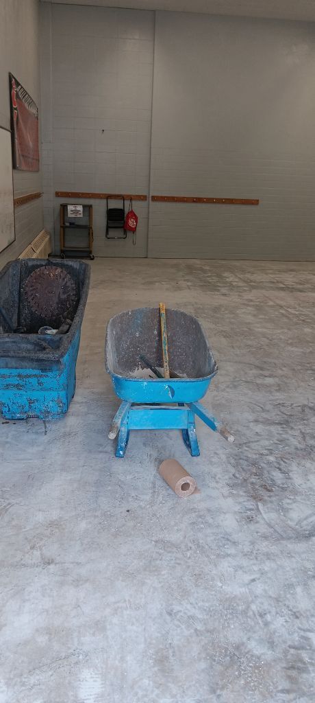 Two blue wheelbarrows with gravel on a concrete floor.