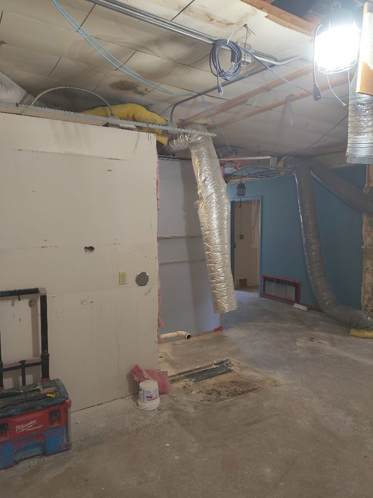 Basement renovation in progress: drywall, ductwork, tools, and electrical conduits.
