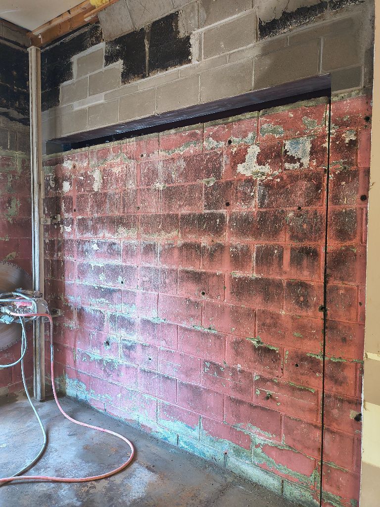 Red brick wall with an opening, partially demolished, in a room under construction.