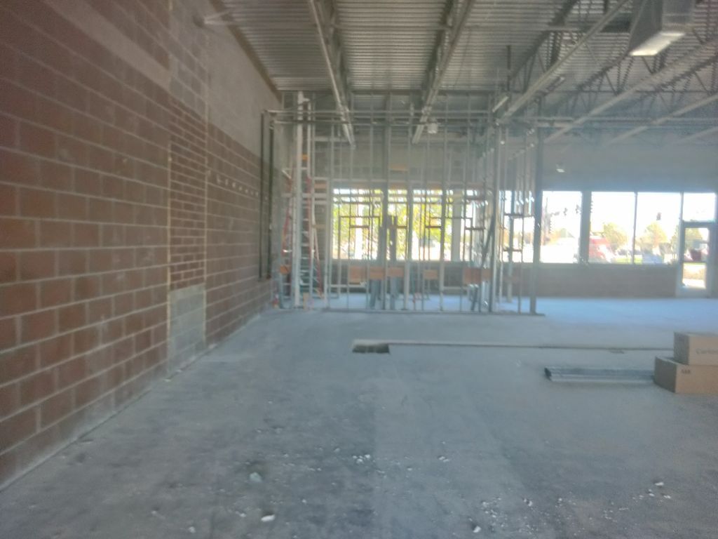 Interior of a commercial space under construction, exposed brick wall, metal studs, concrete floor.