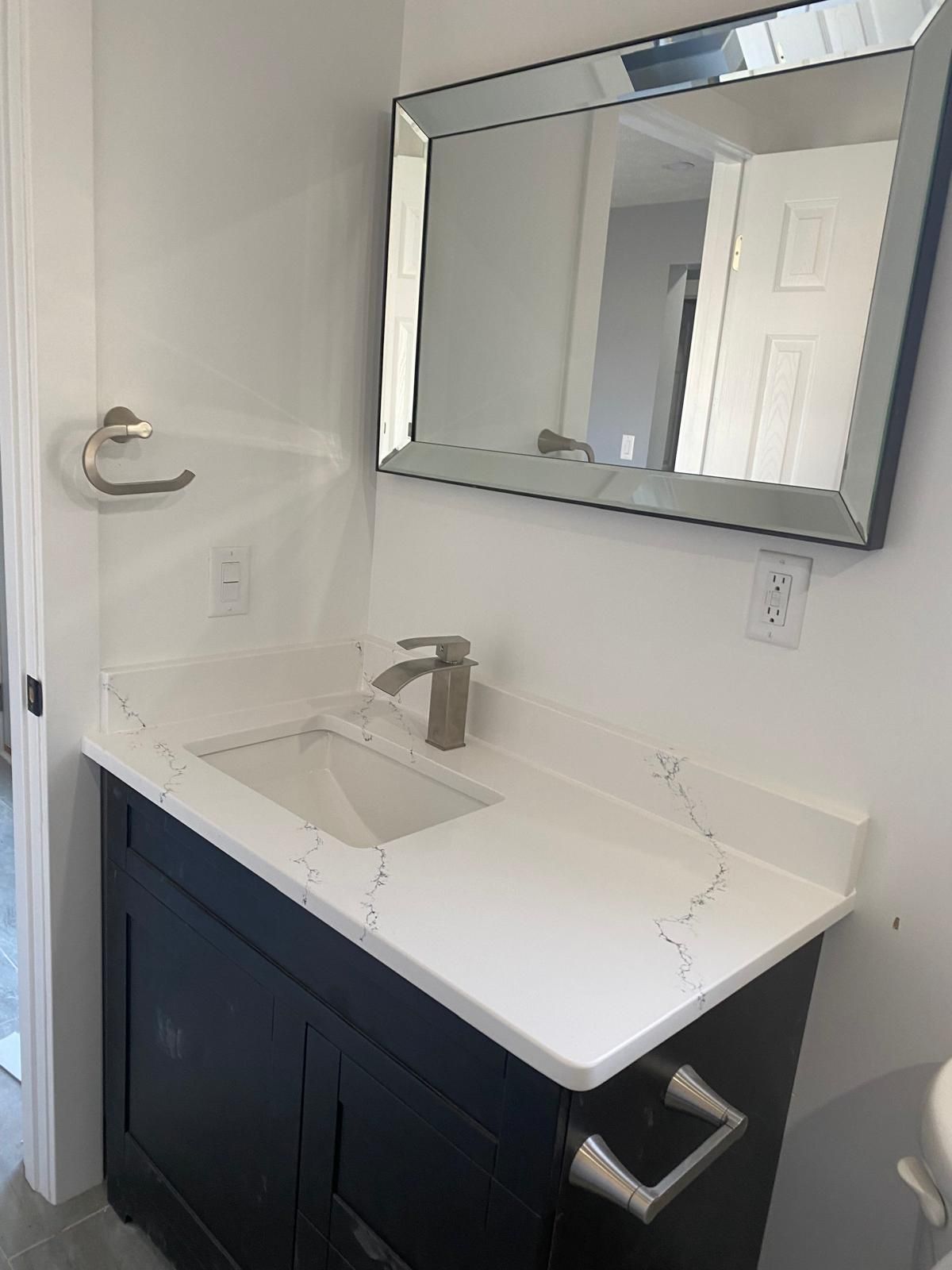 A bathroom with a sink , mirror and vanity.