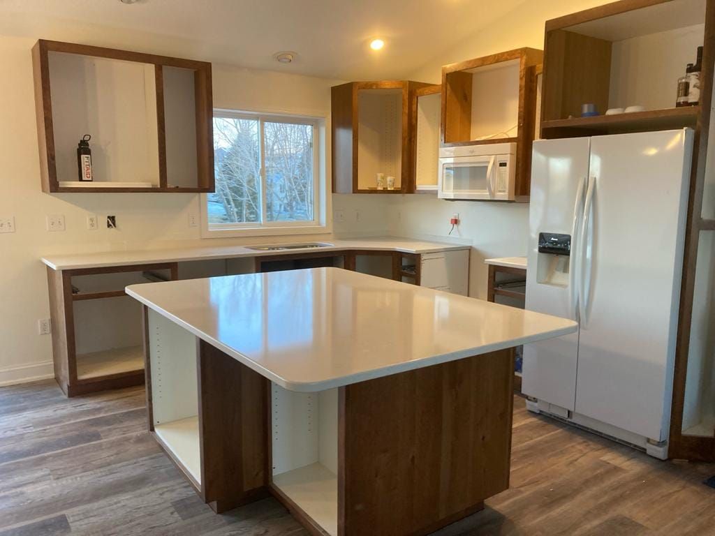 A kitchen with a large island in the middle and a refrigerator.