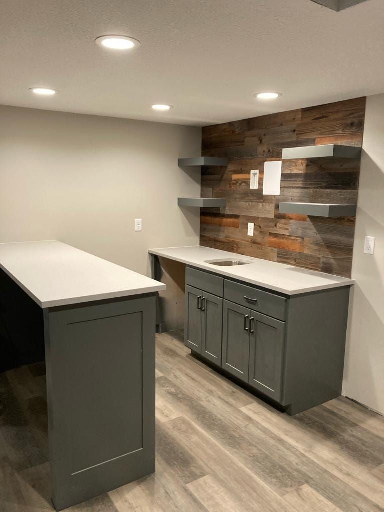 A kitchen with gray cabinets and a wooden wall.