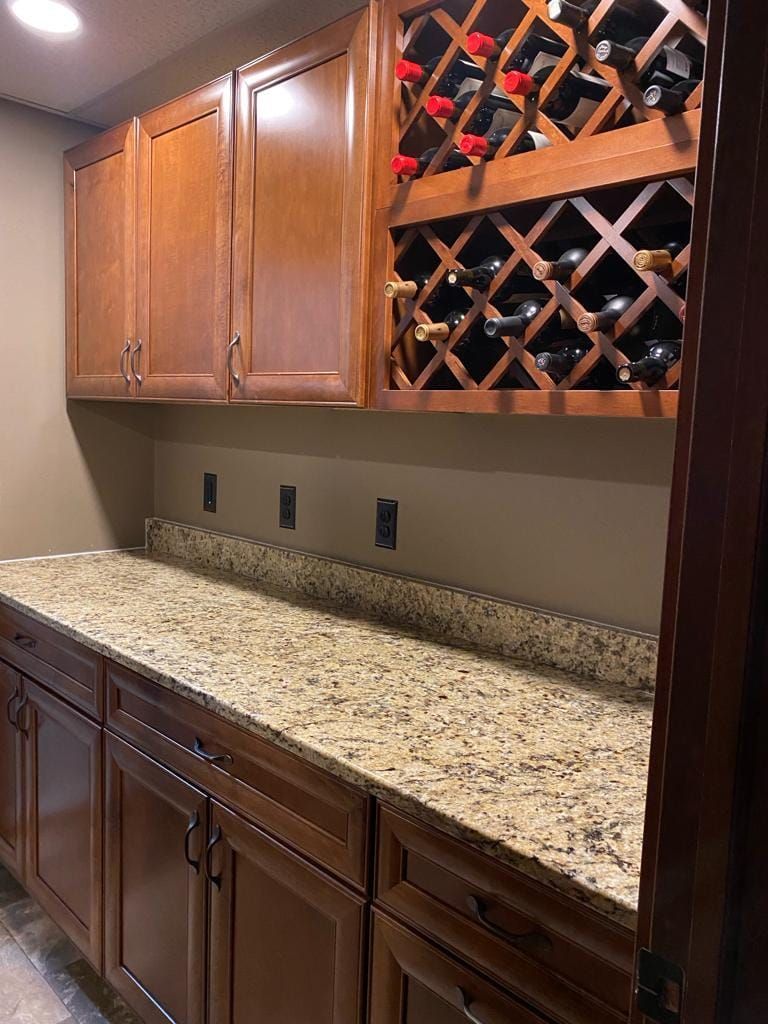 A kitchen with granite counter tops and wooden cabinets and a wine rack.