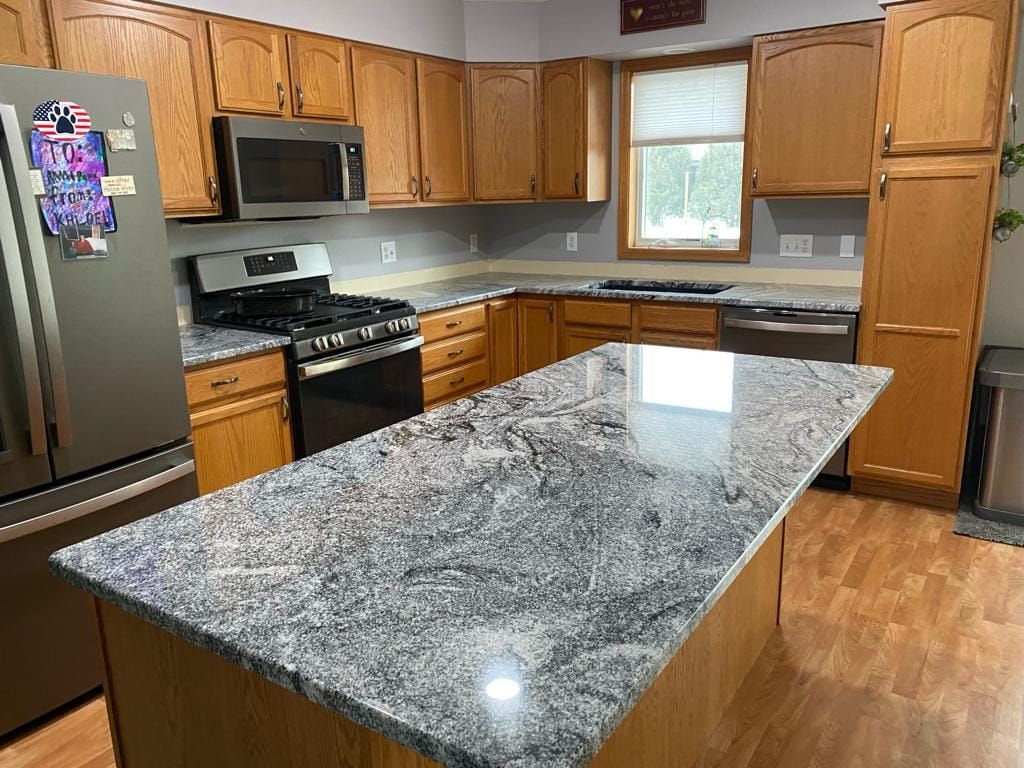 A kitchen with granite counter tops , stainless steel appliances , and wooden cabinets.