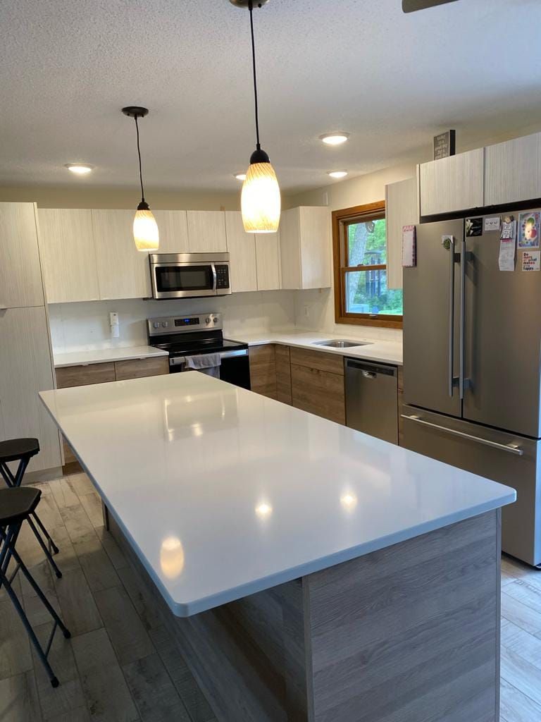 A kitchen with a large island in the middle and stainless steel appliances.